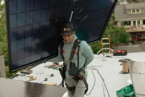 Worker carrying solar panel on roof