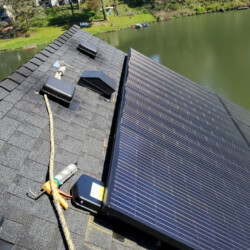 Solar panels installed on a roof with water in the background.